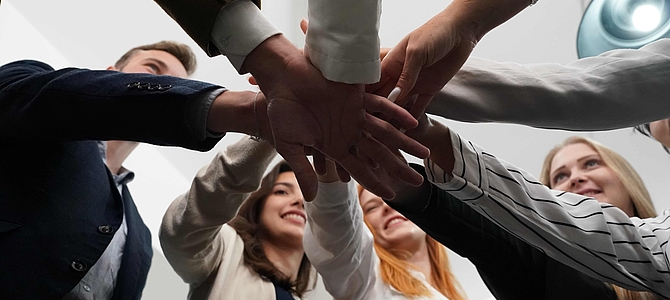 Mehrere Menschen legen Hände aufeinander